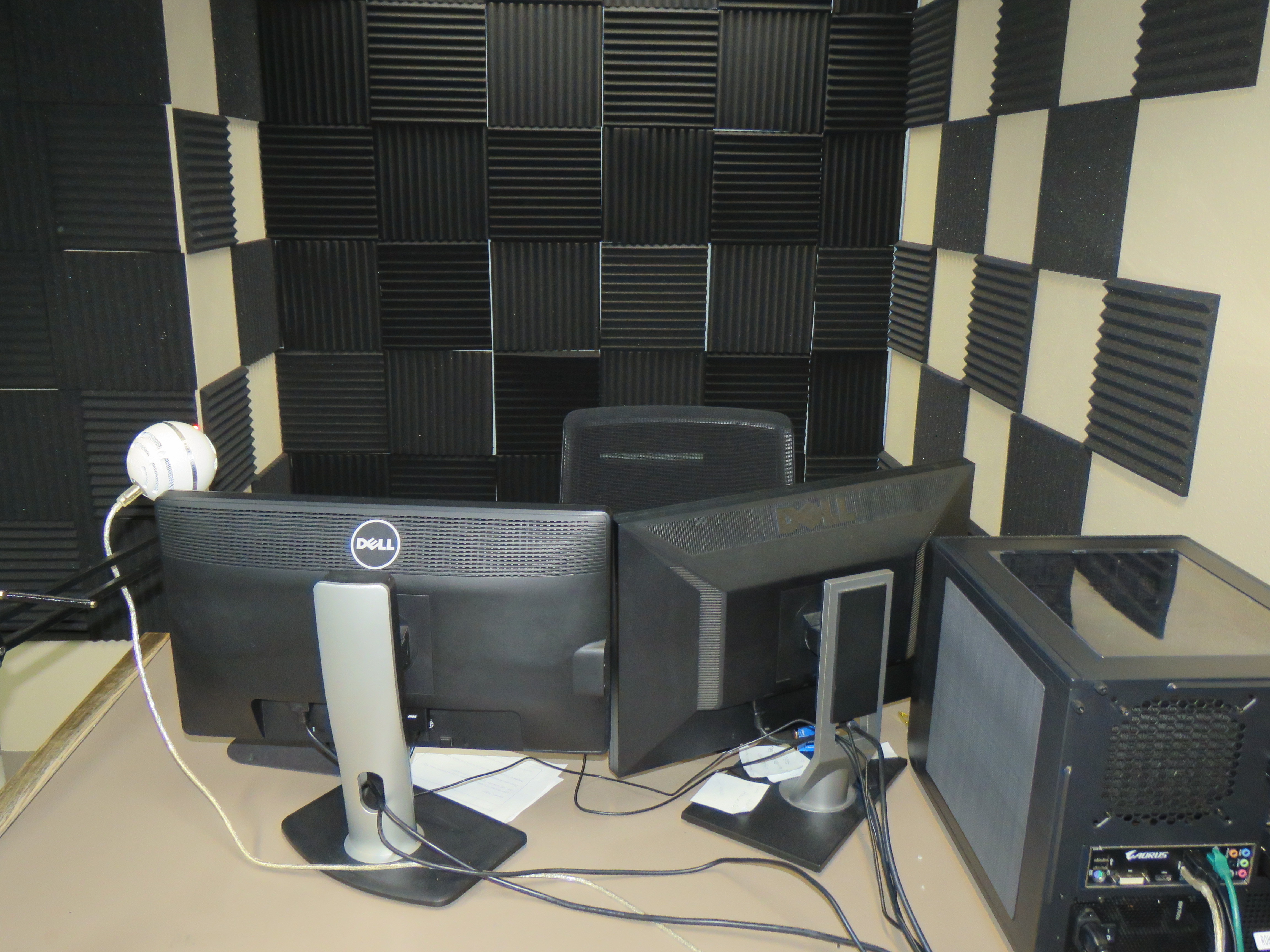 Production room dual-monitor desktop and equipment in room with sound baffling
