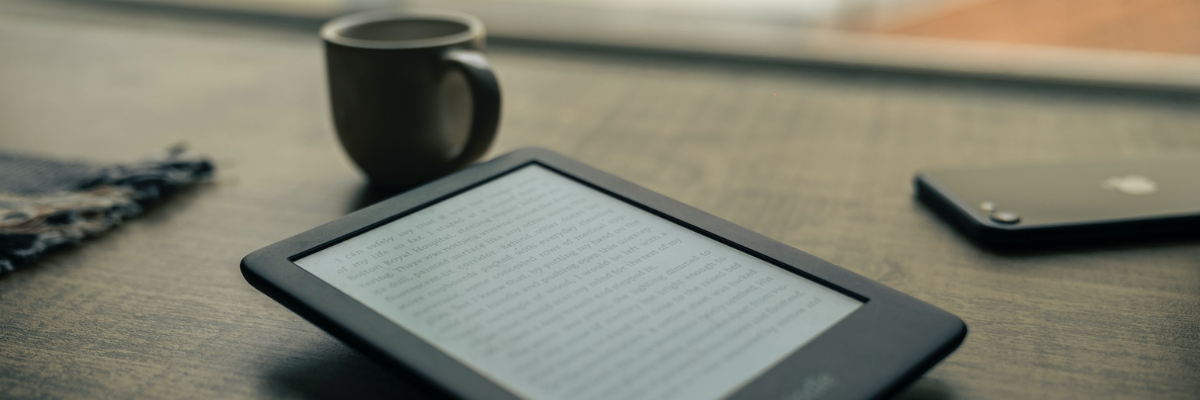 eReader, phone, and mug on table