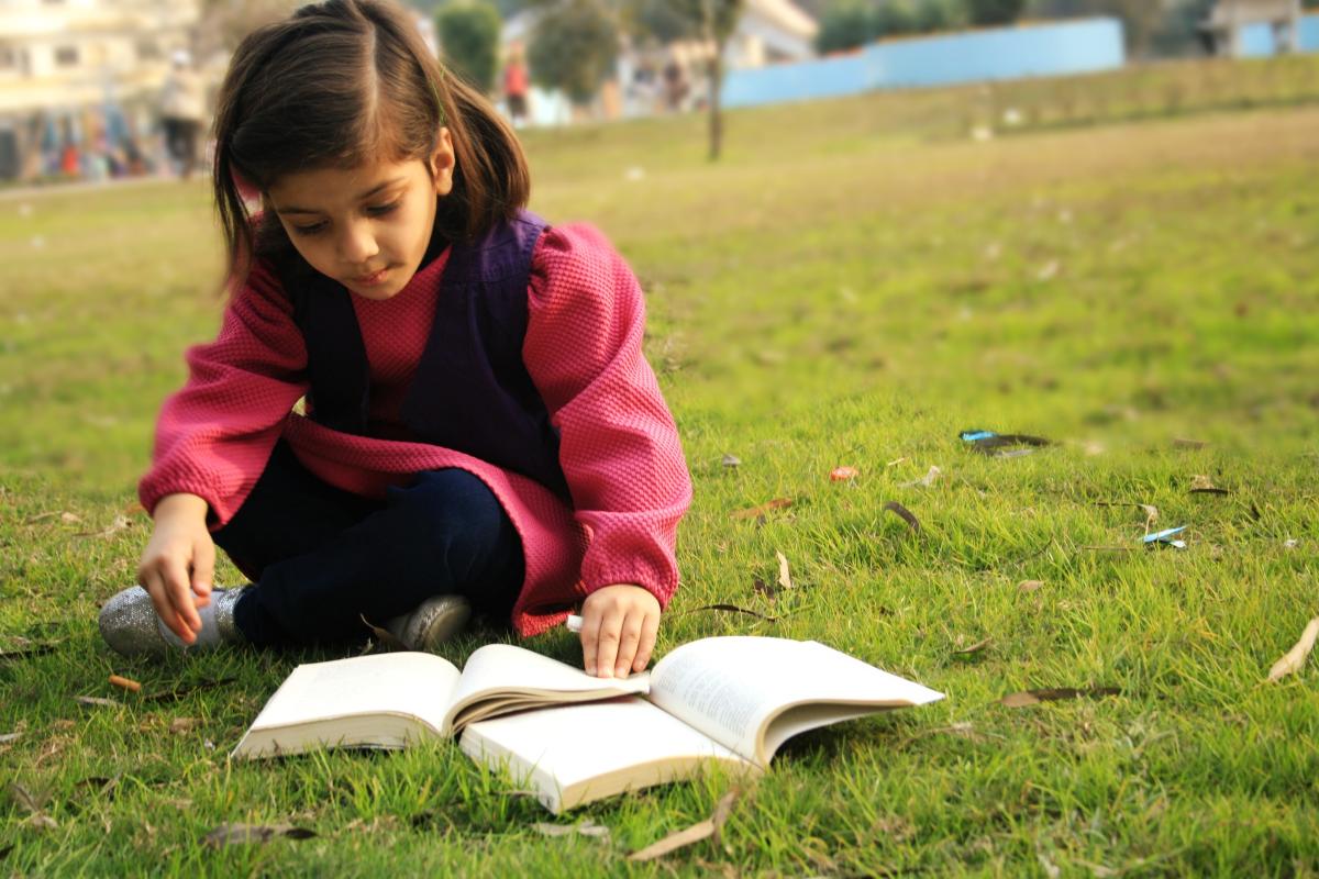 Young girl reading book outside